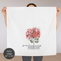 Person holding an extra large white tea towel with a floral design and text 'your love is my foundation' on a plain background