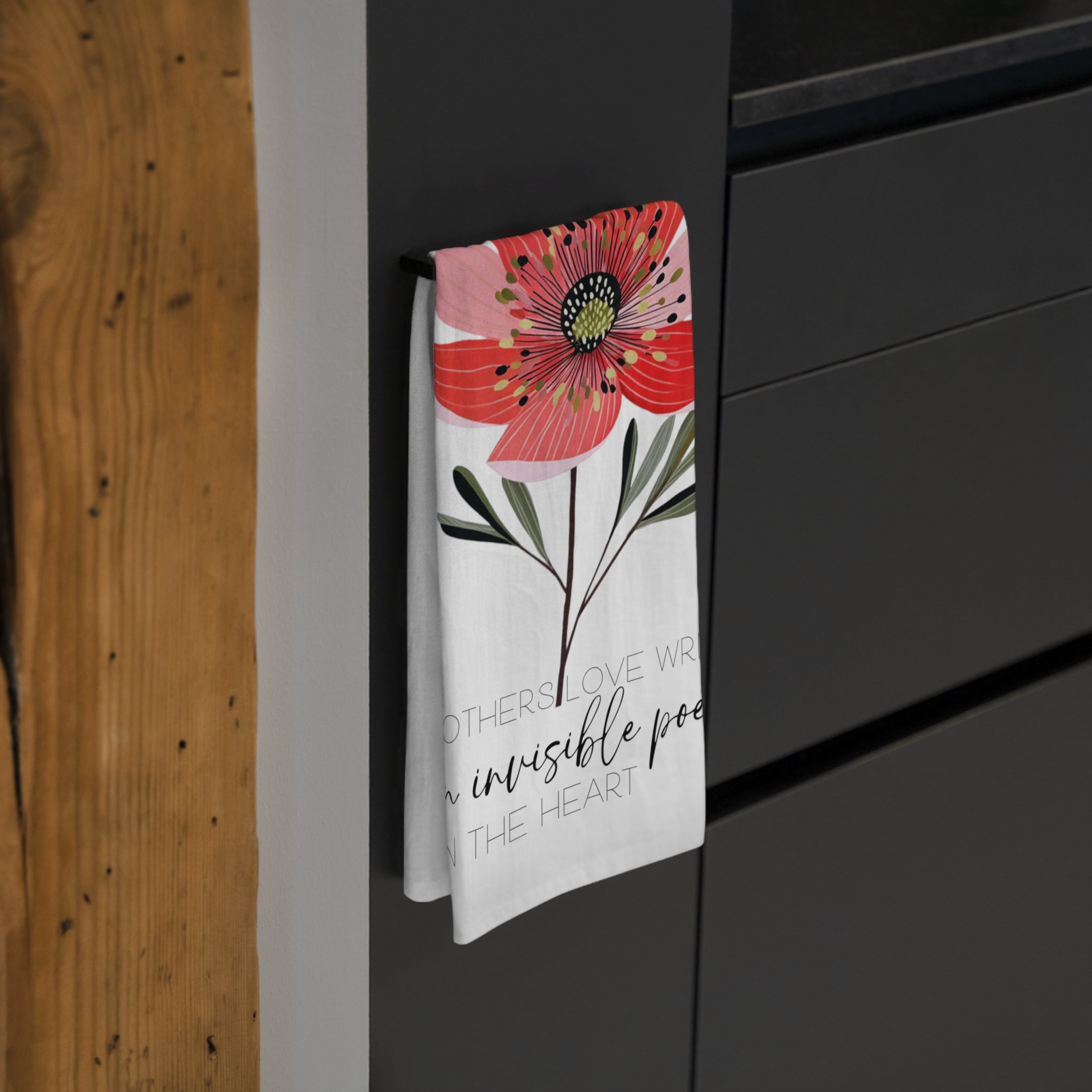 Floral-themed towel hanging on a black cabinet with wooden wall background