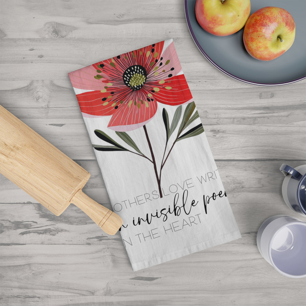 Floral tea towel with text on a kitchen counter with apples and a rolling pin.