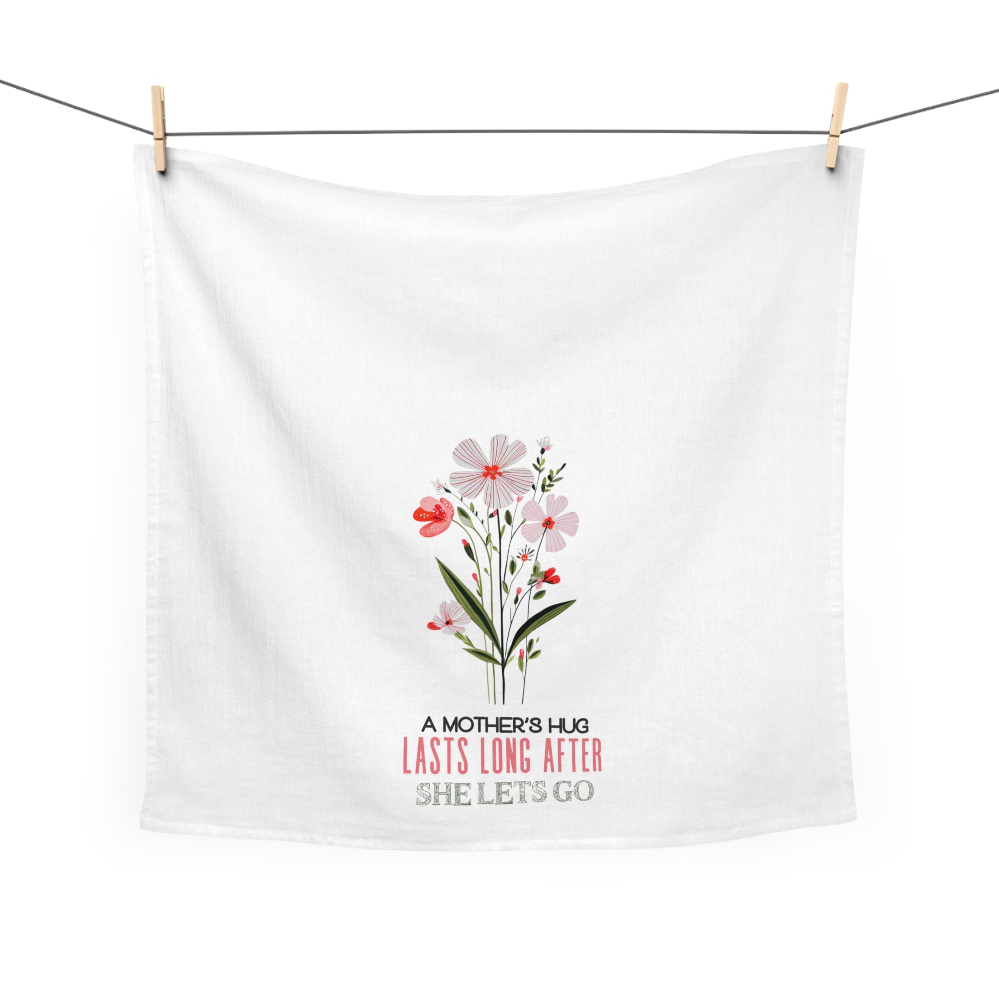 White tea towel with floral design and text hanging on a line