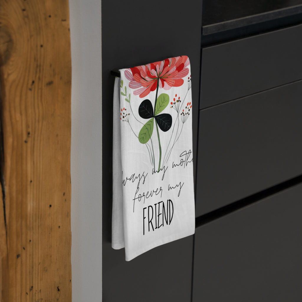 Folded floral kitchen towel with text hanging on a black cabinet.