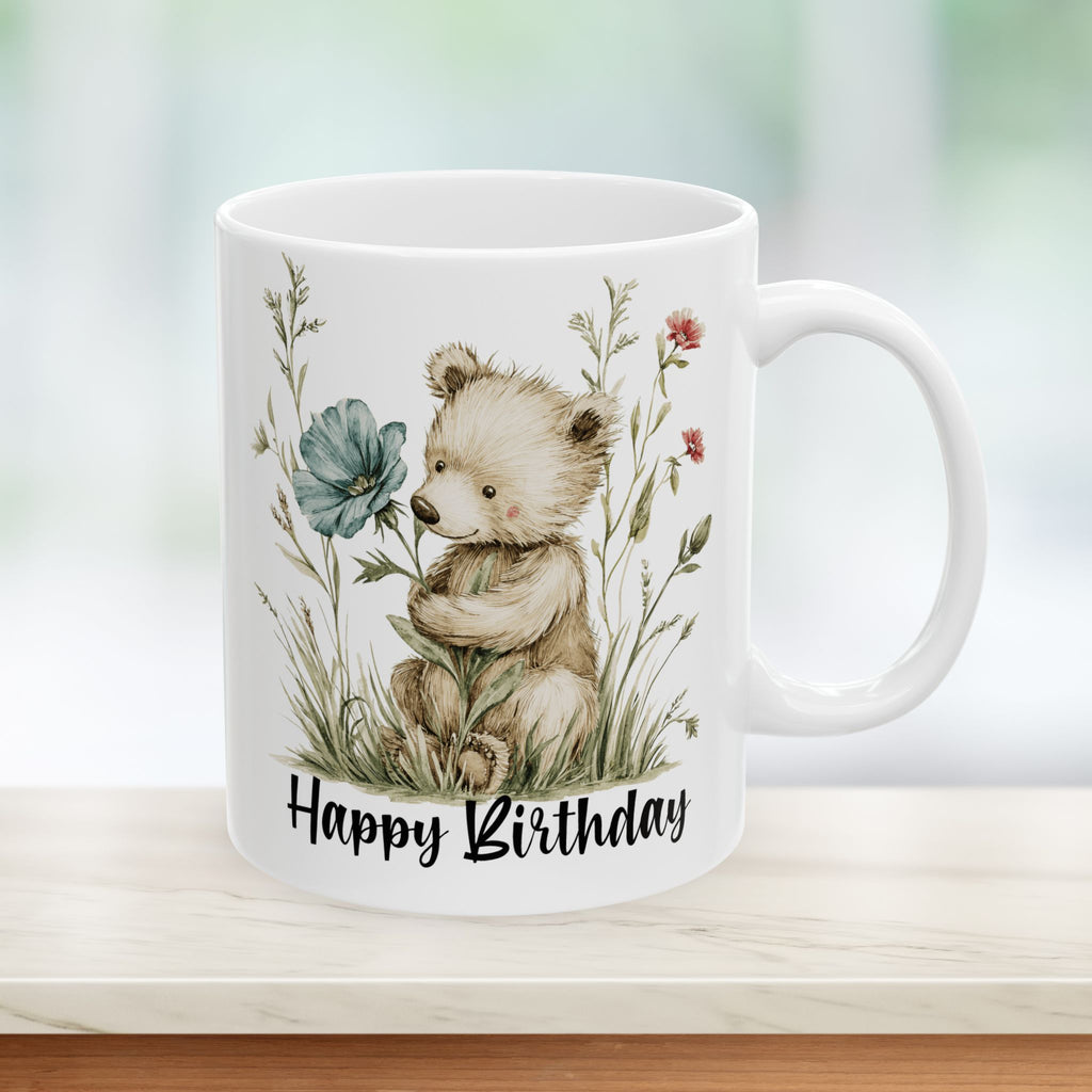 White mug with a bear holding a flower and 'Happy Birthday' text on a blurred background