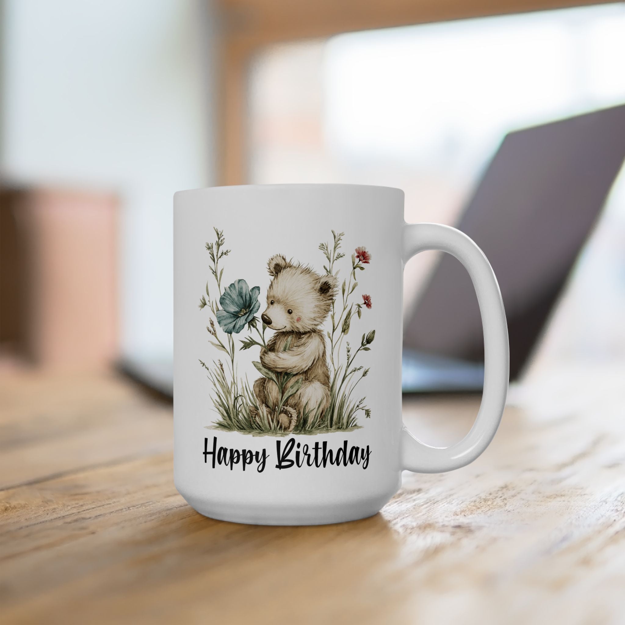 White mug with a teddy bear and floral design with text 'Happy Birthday' on a wooden surface