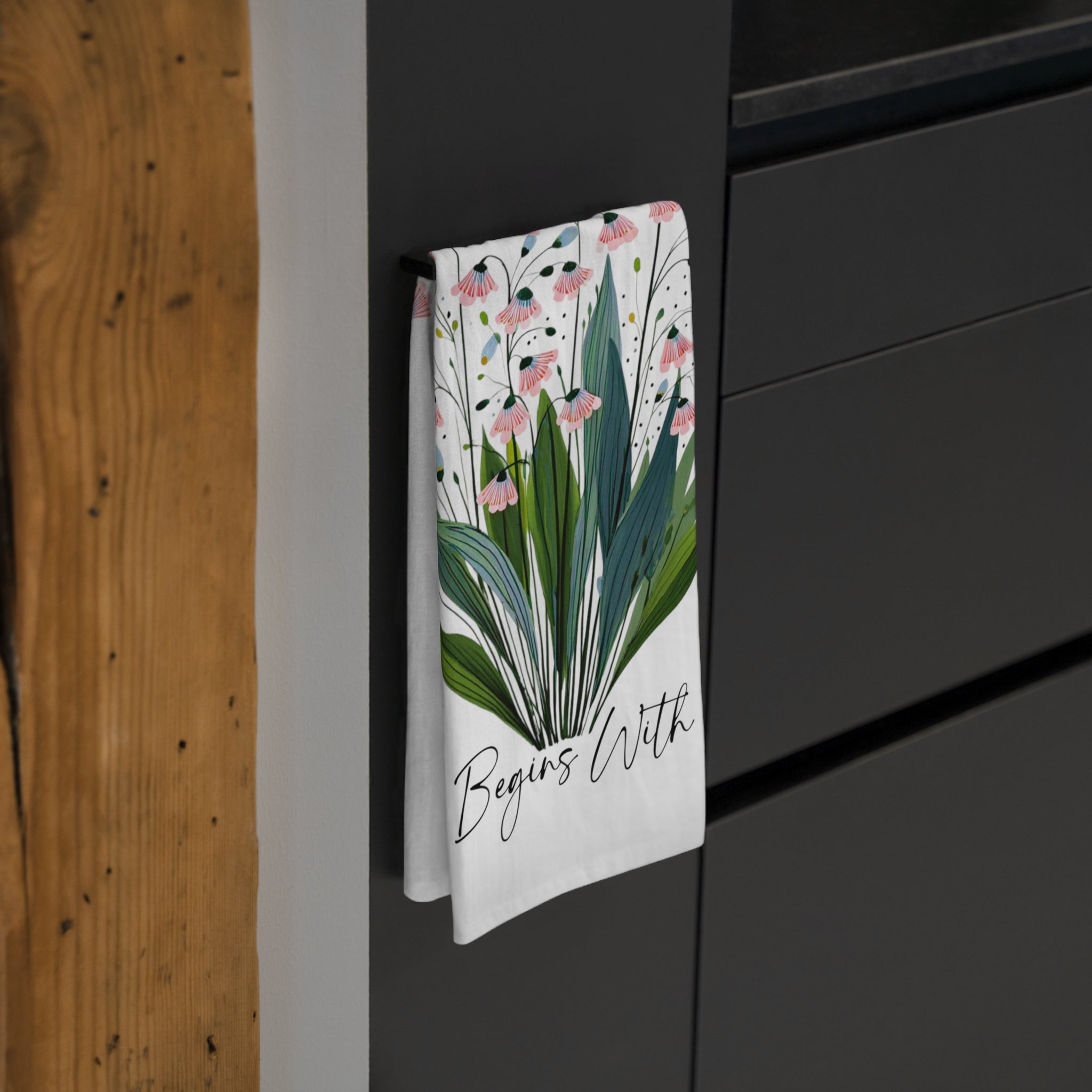 Floral towel hanging on a black cabinet with a wooden wall background