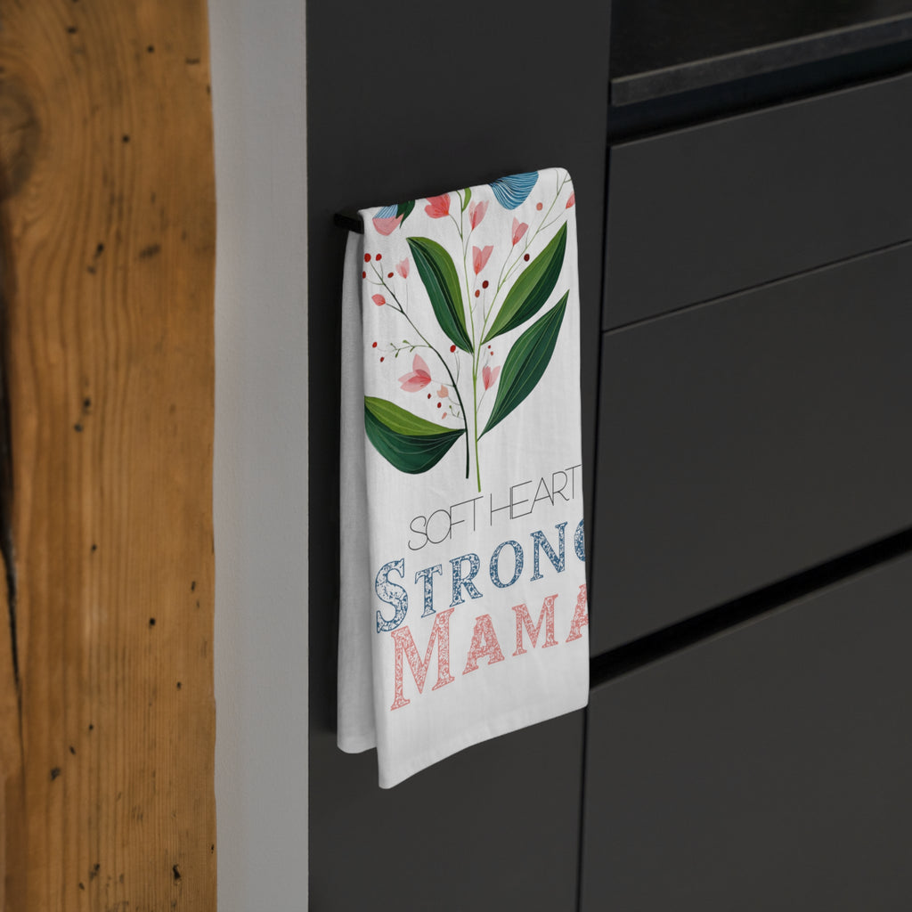 Tea towel with floral design and text hanging on a black cabinet.
