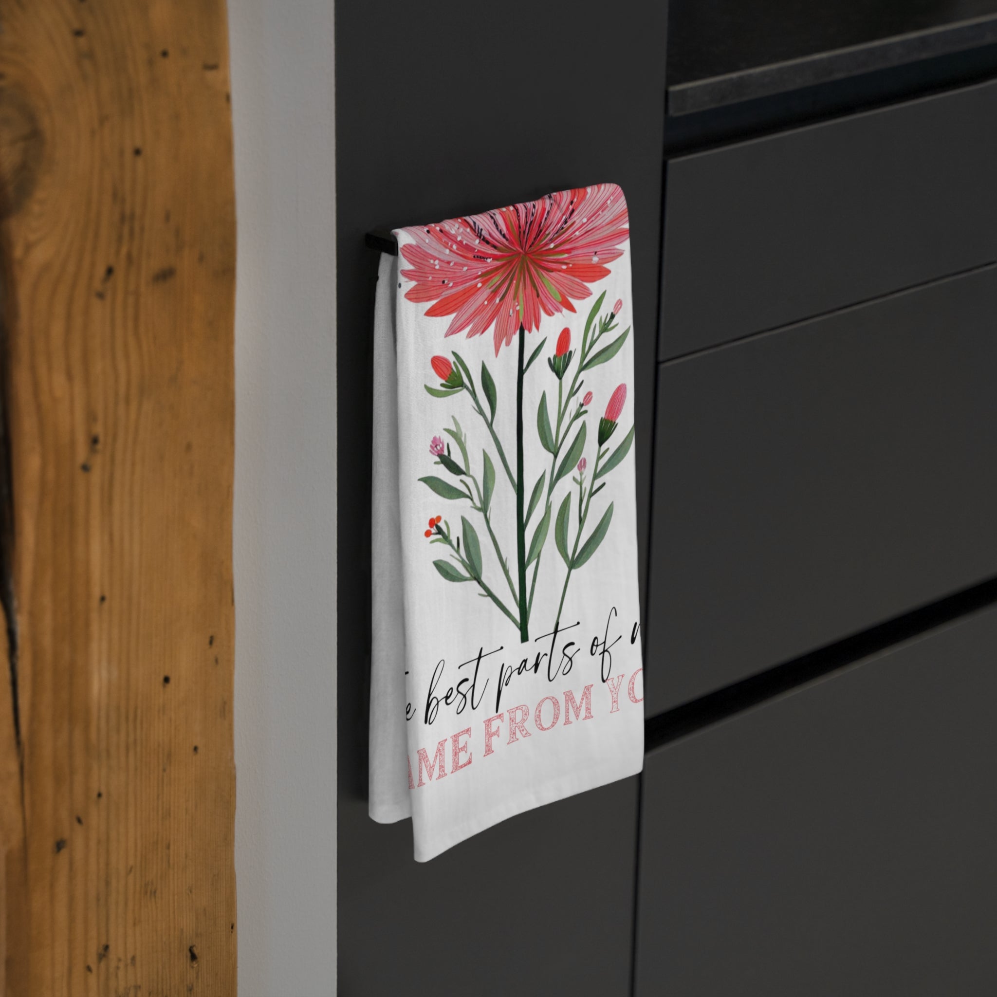 Floral design tea towel hanging on a black cabinet.