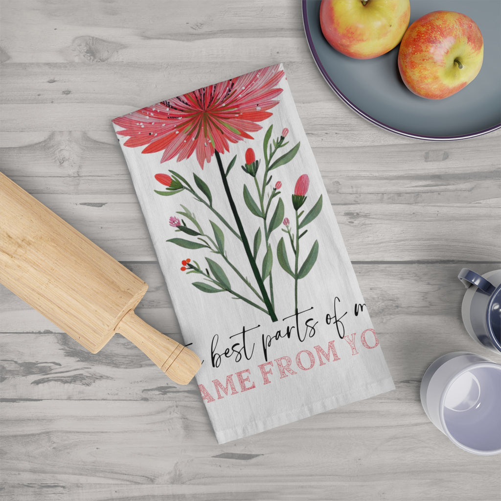 Floral towel with text on a wooden surface with apples and a rolling pin.