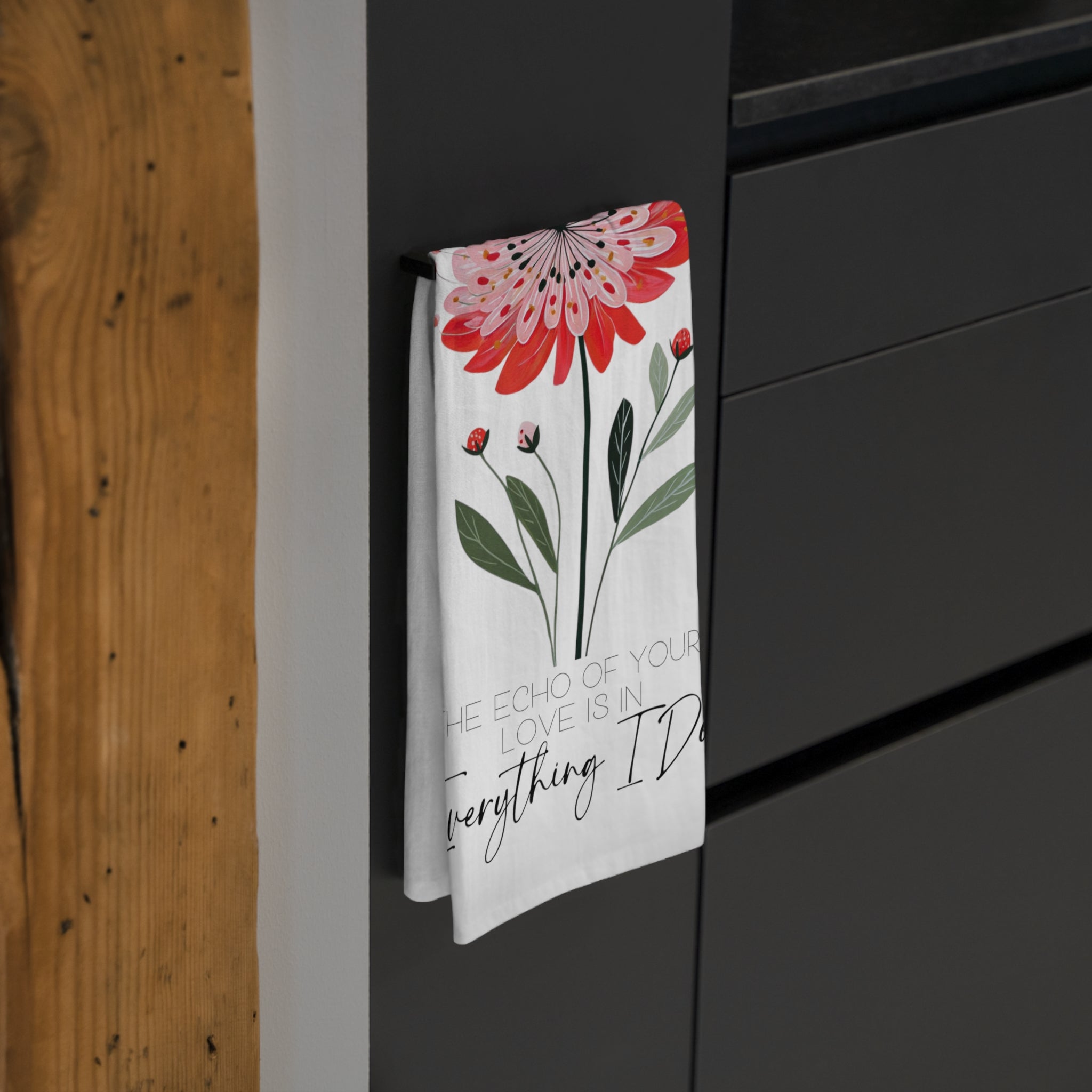 Floral towel with text hanging on a black cabinet.