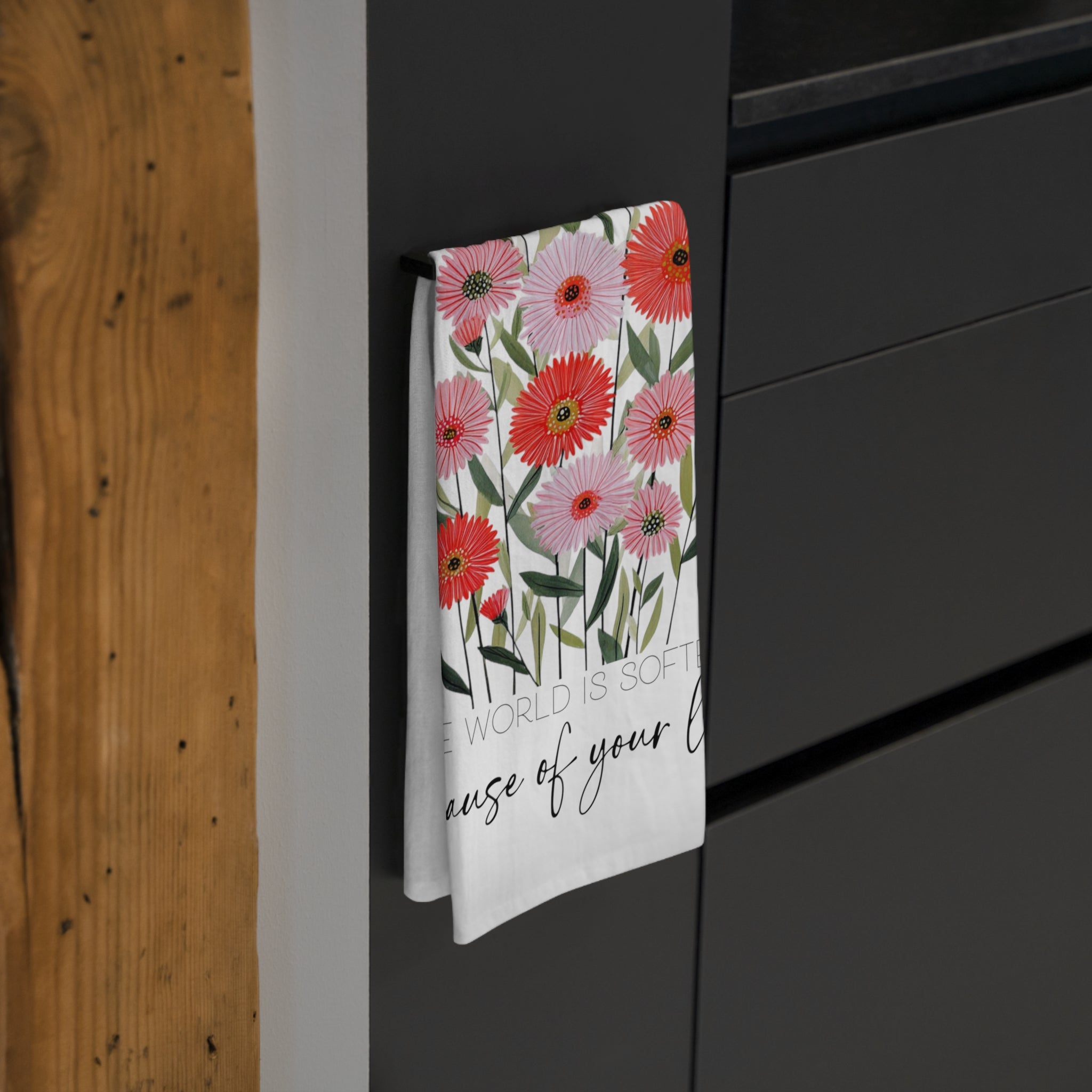 Floral patterned towel hanging on a black cabinet with wooden wall background