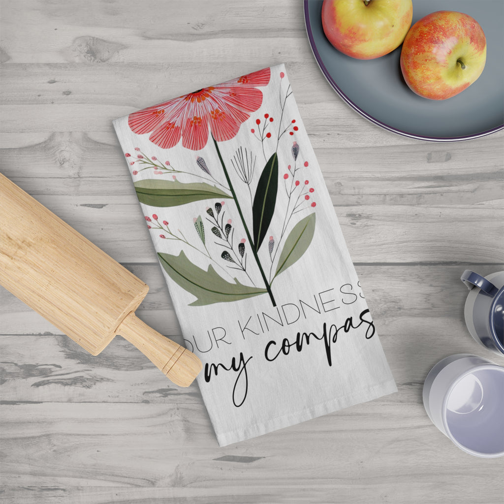 Floral towel with text on a wooden surface with apples and a rolling pin.