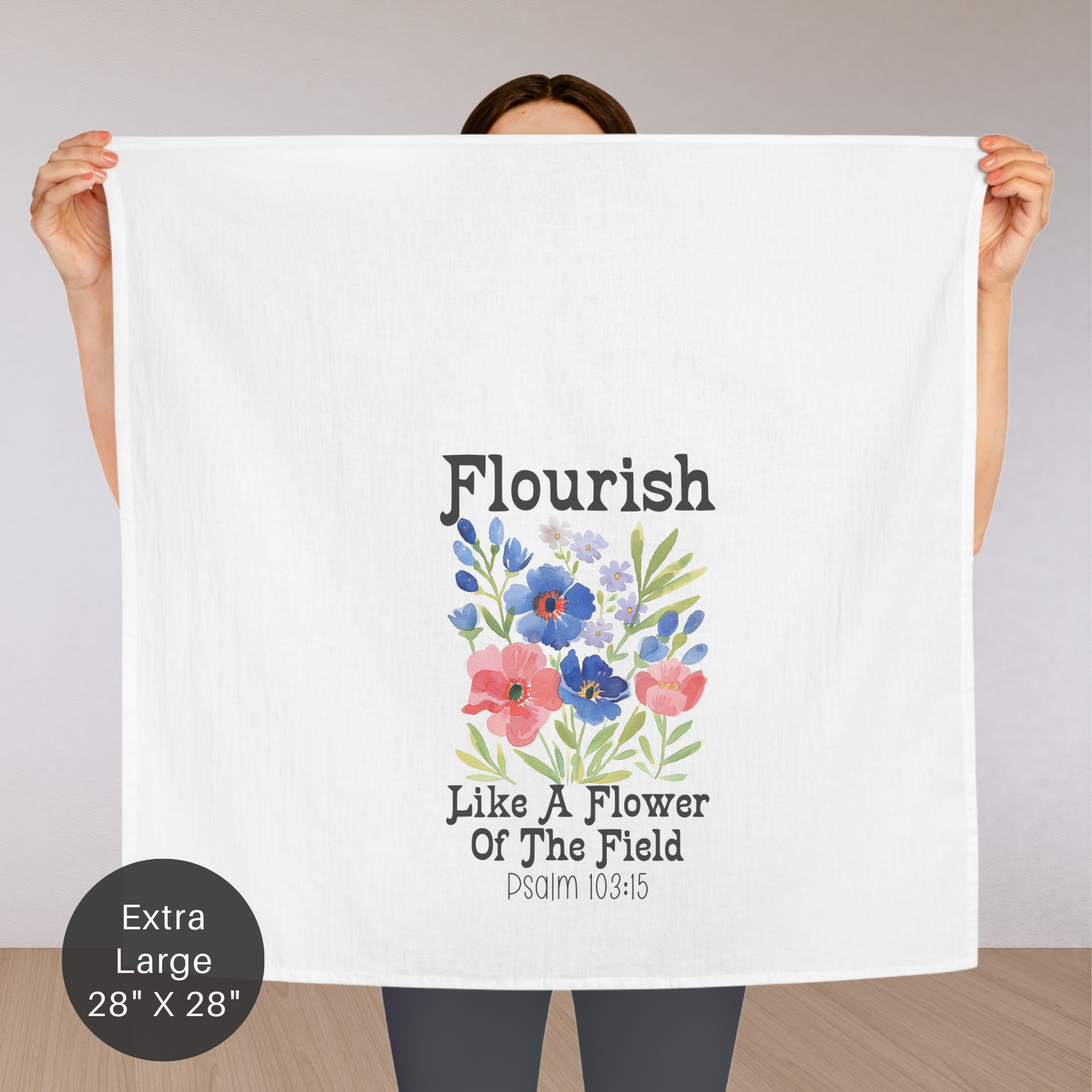 Person holding an extra large white tea towel with floral design and text.