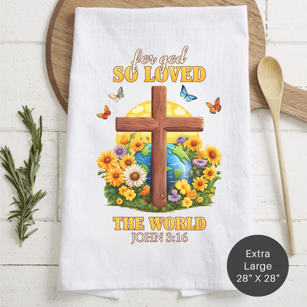 White tea towel with cross and floral design, featuring text 'For God so loved the world John 3:16' on a wooden surface.