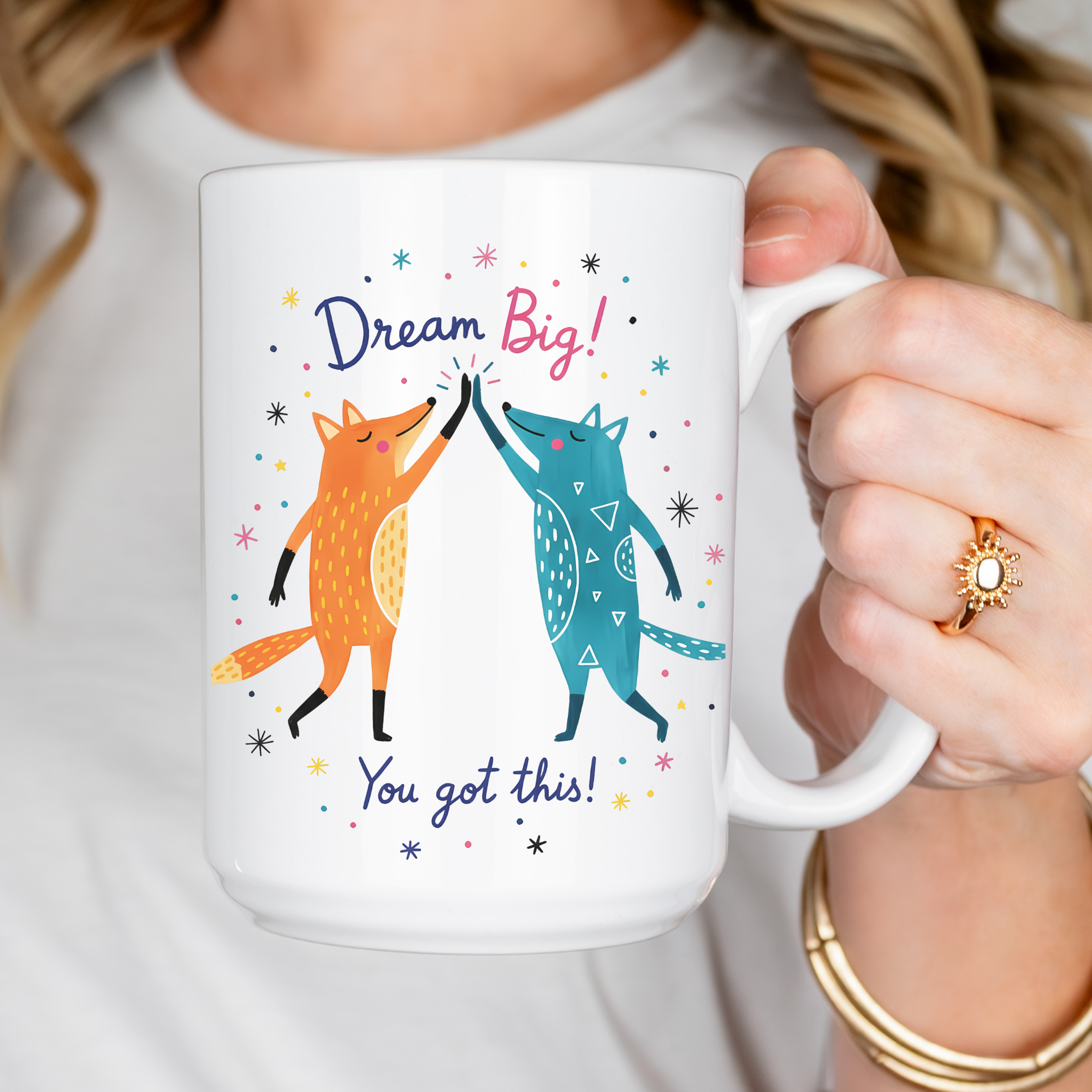 Person holding a mug with foxes and motivational text