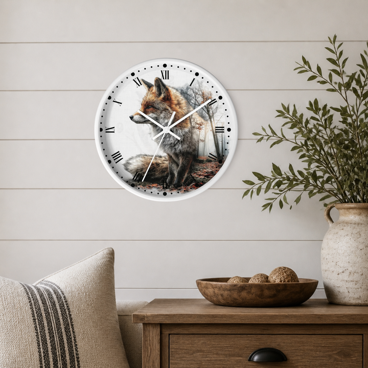 A round wall clock with a white frame and a detailed illustration of a fox on the face, mounted on a light beige shiplap wall above a wooden side table with a plant and decorative bowl.