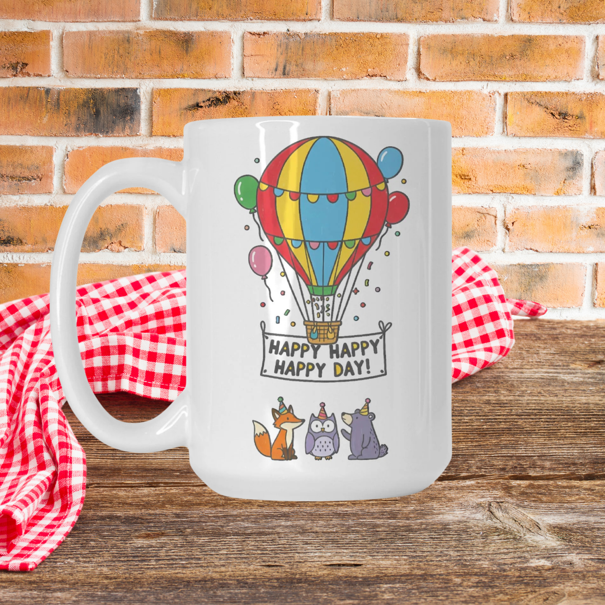 White mug with colorful hot air balloon design and text 'Happy Happy Happy Day!' on a wooden surface with a brick wall background.