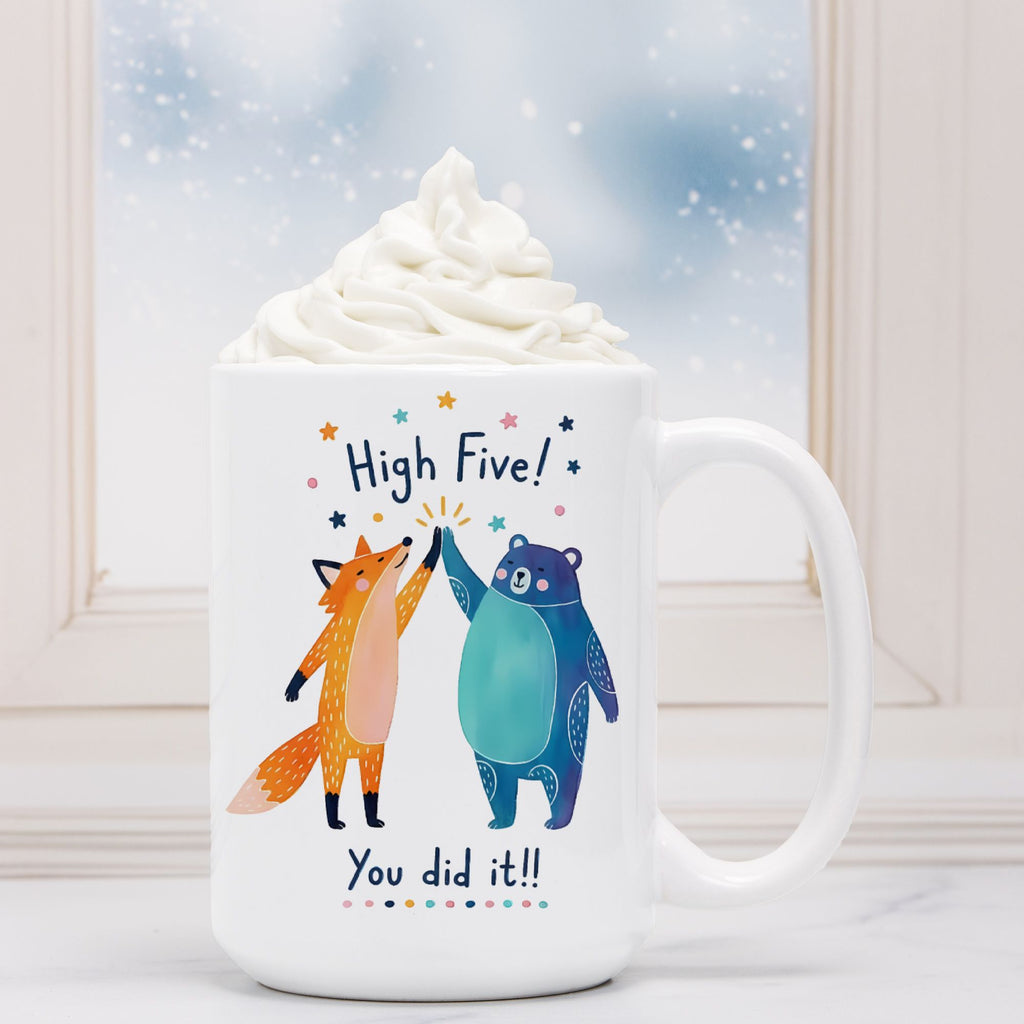 White mug with cartoon fox and bear design and text 'High Five! You did it!' on a snowy background.