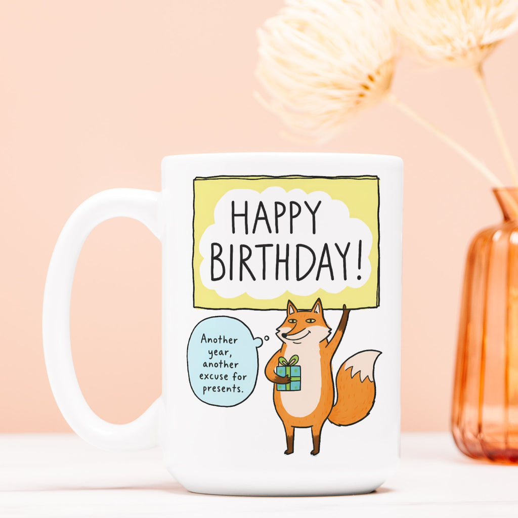 White mug with a fox illustration and 'Happy Birthday!' text on a light pink background