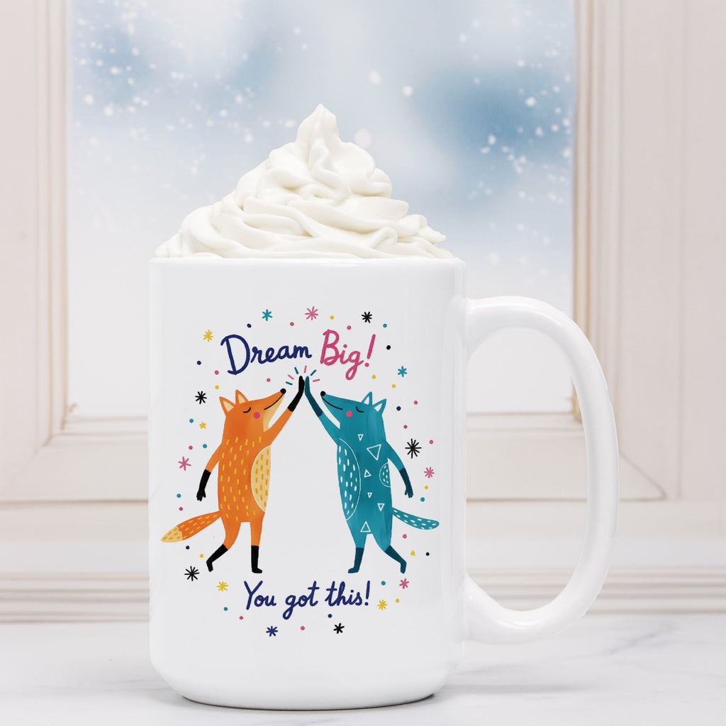 White mug with fox design and motivational text, filled with hot chocolate and whipped cream.