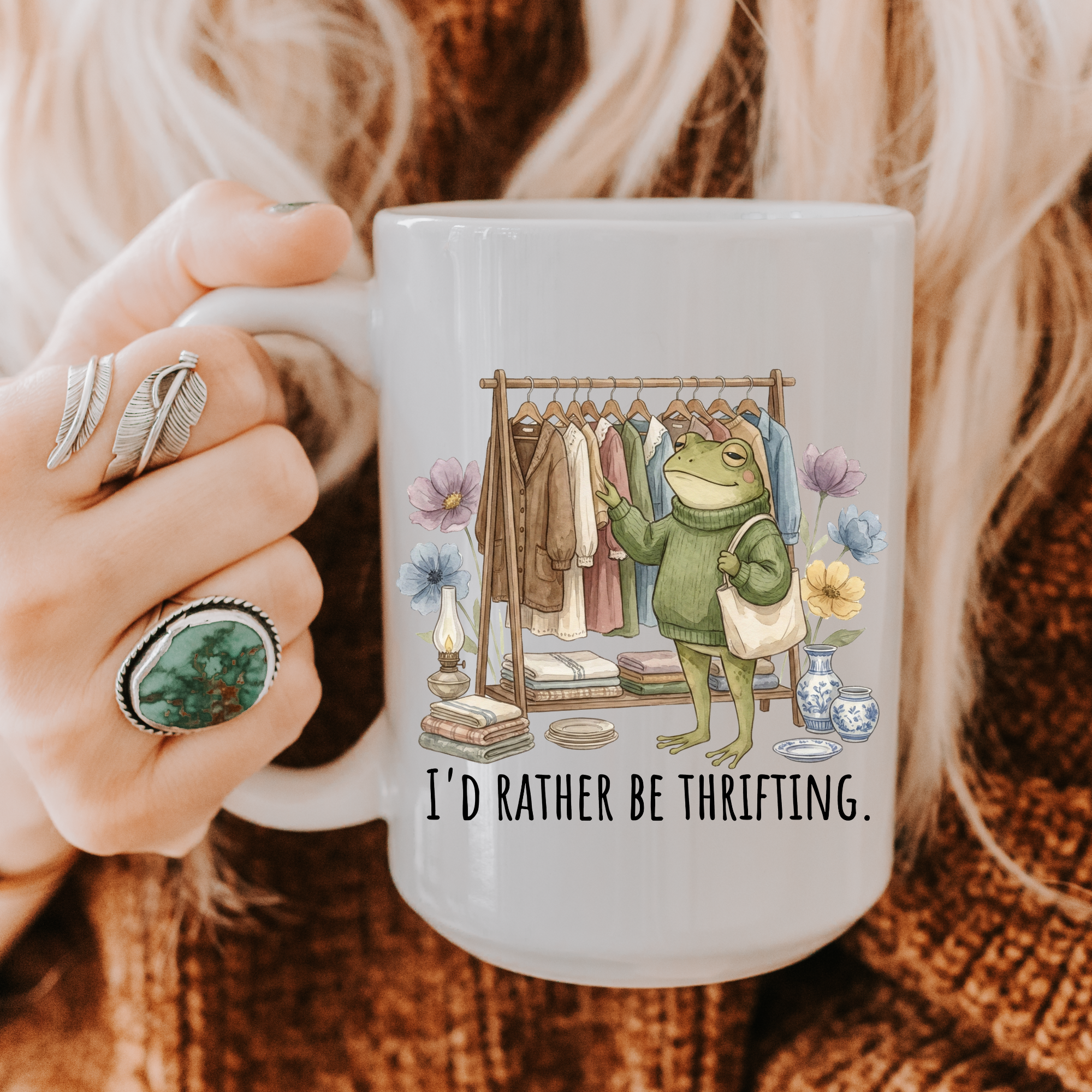 Person holding a 15oz. mug with a frog graphic and text 'I'd Rather Be Thrifting' on a warm background.