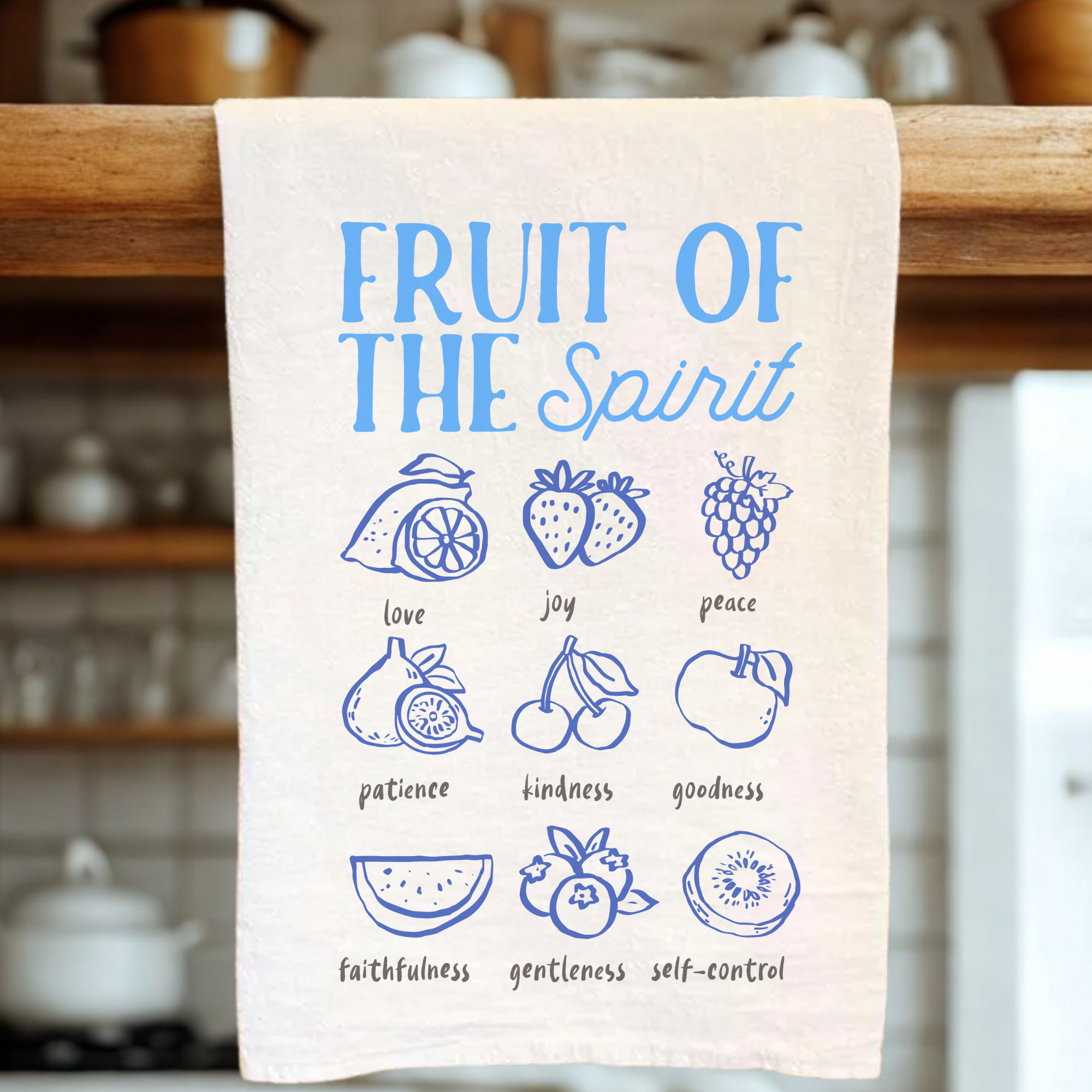 Kitchen towel with 'Fruit of the Spirit' design on a wooden rack.