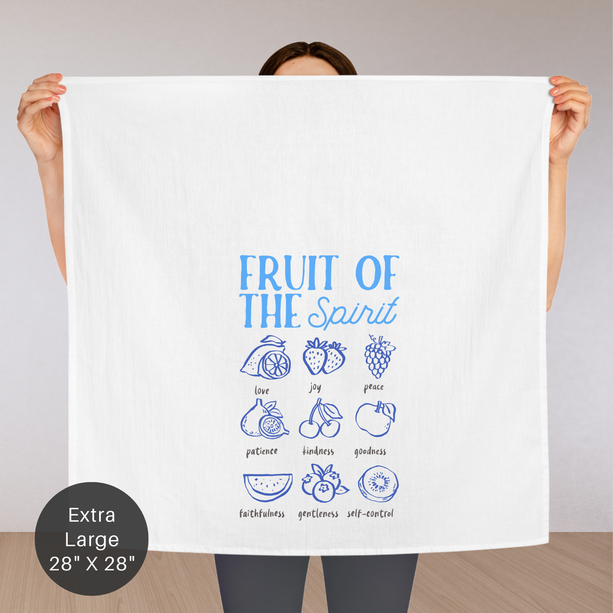 Person holding an extra large white tea towel with 'Fruit of the Spirit' design against a plain background