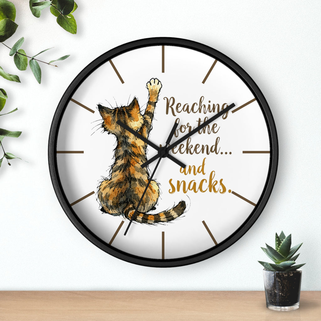 Round black wall clock with a cat design and text 'Reaching for the weekend... and snacks.' on a white background.