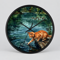 Round wall clock with a black frame and a printed illustration of an orange tabby cat reaching into a pond, with ducks and greenery in the background.
