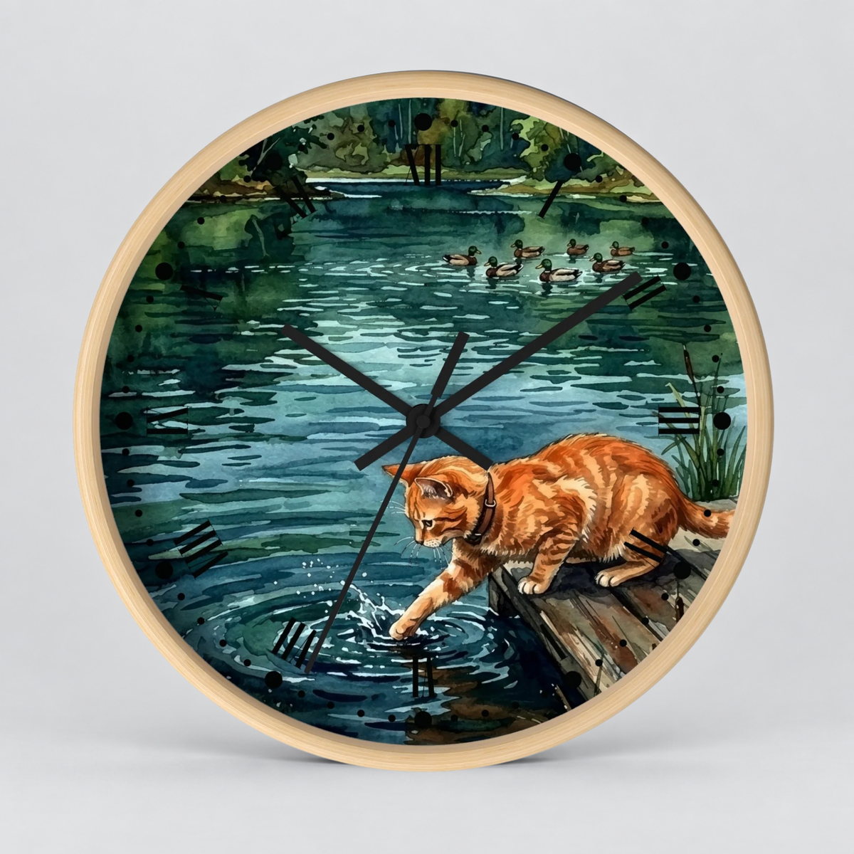 Round wall clock with a light wood frame and a printed illustration of an orange tabby cat reaching into a pond, with ducks and trees in the background. The clock is shown against a light gray studio backdrop.