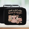 black lunch bag with vintage design and text 'just a girl who loves to thrift' on a counter with a light background.