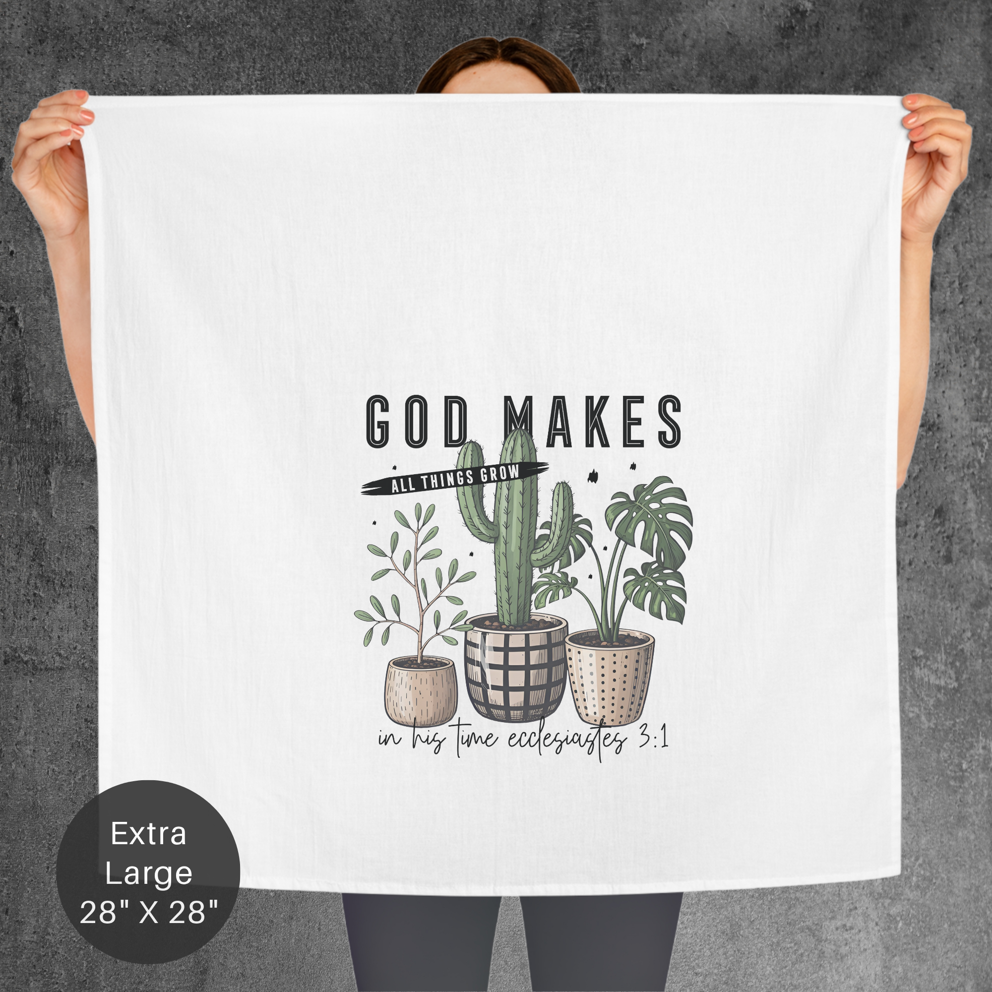 Person holding an extra large tea towel with cactus plant illustrations and text against a gray background