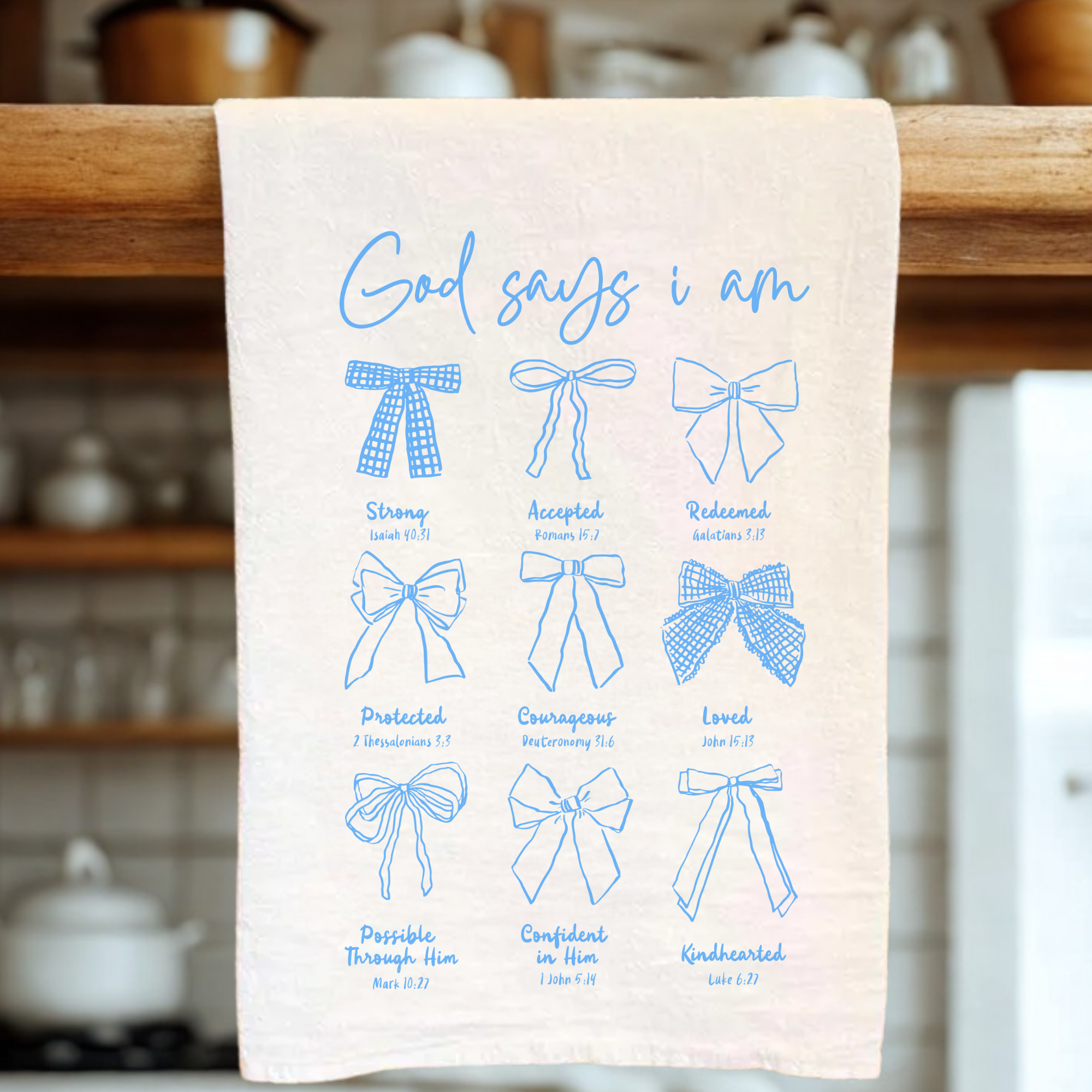 white tea towel with blue text and bow illustrations on a wooden rack in a kitchen setting