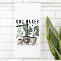Decorative tea towel with cacti and plants on a white tiled wall.