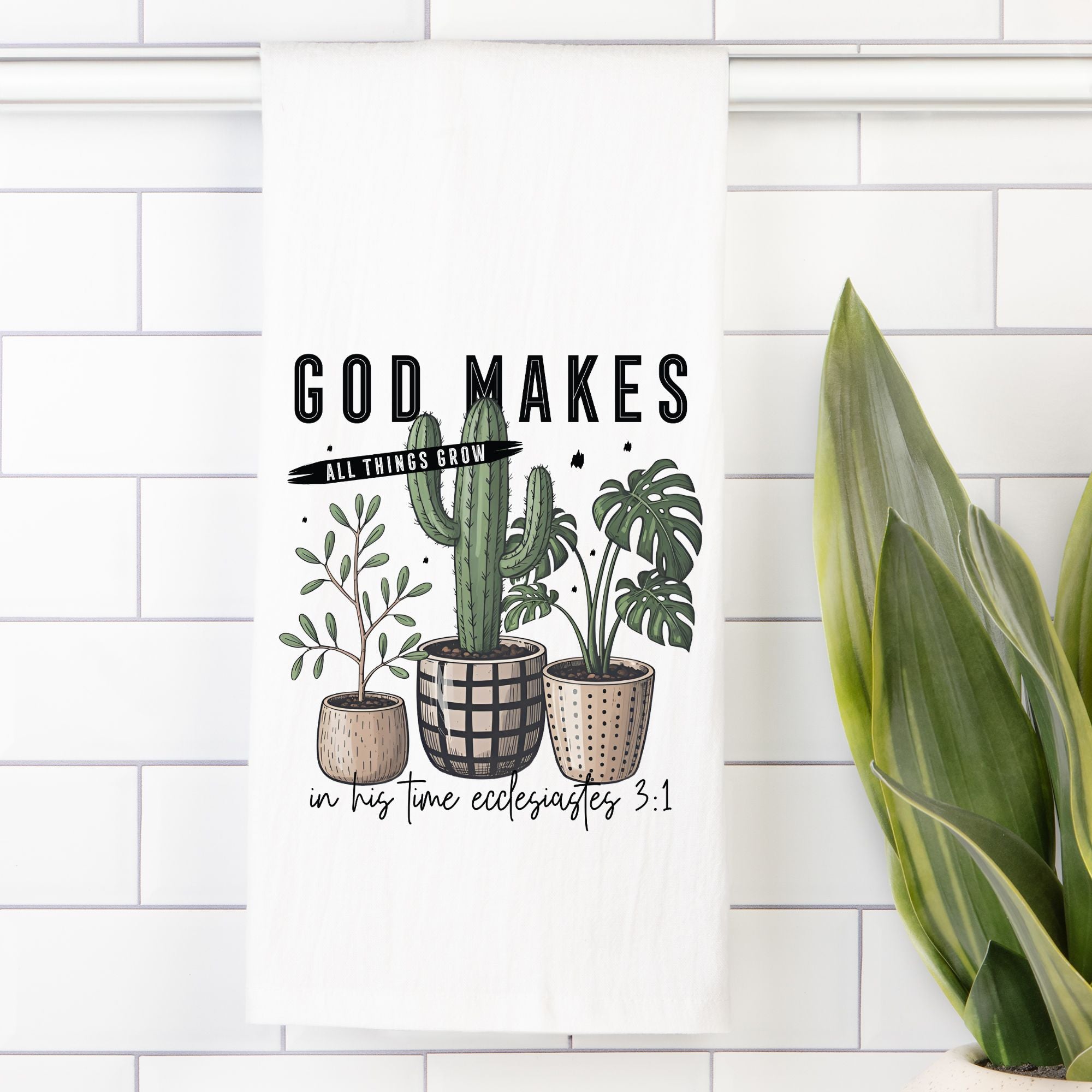 Decorative tea towel with cacti and plants on a white tiled wall.