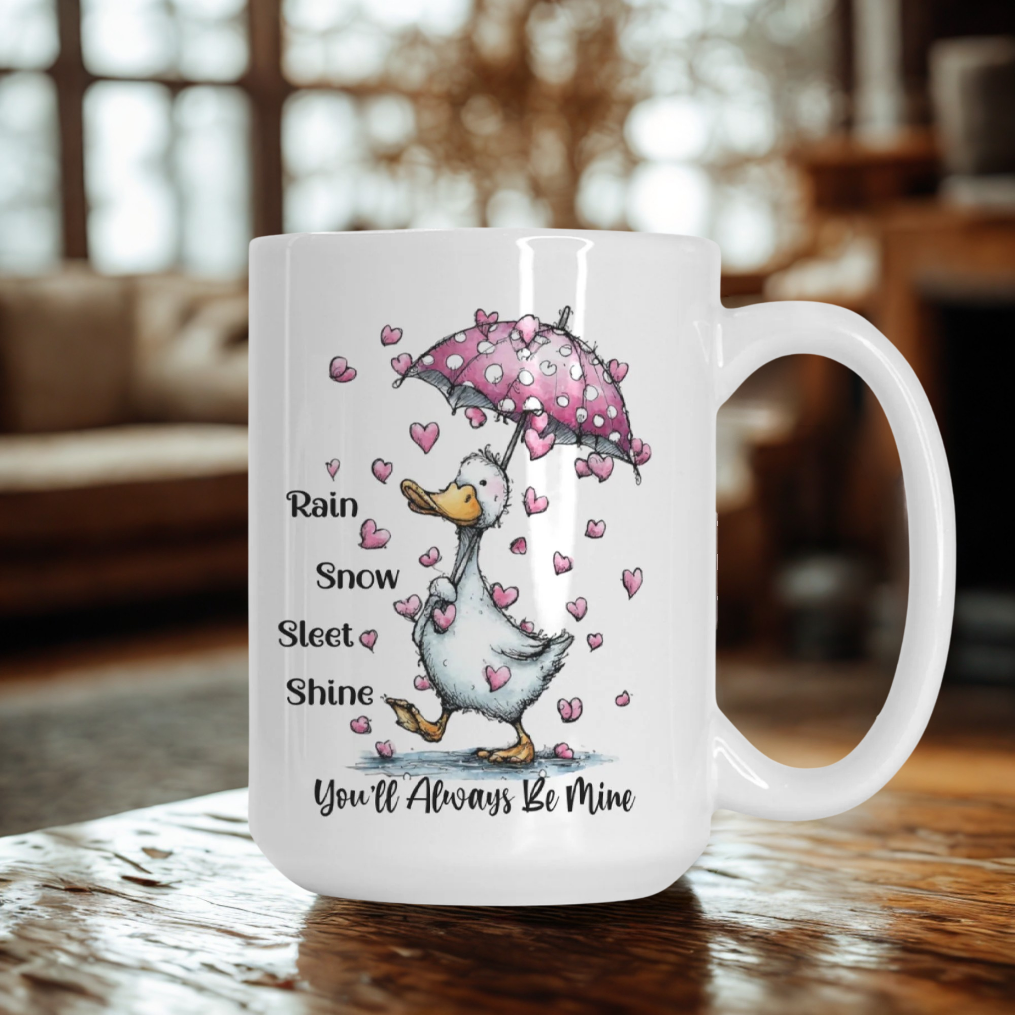 Mug with a cartoon goose holding a pink umbrella and heart pattern, with text 'Rain Snow Sleet Shine You'll Always Be Mine' on a wooden surface.