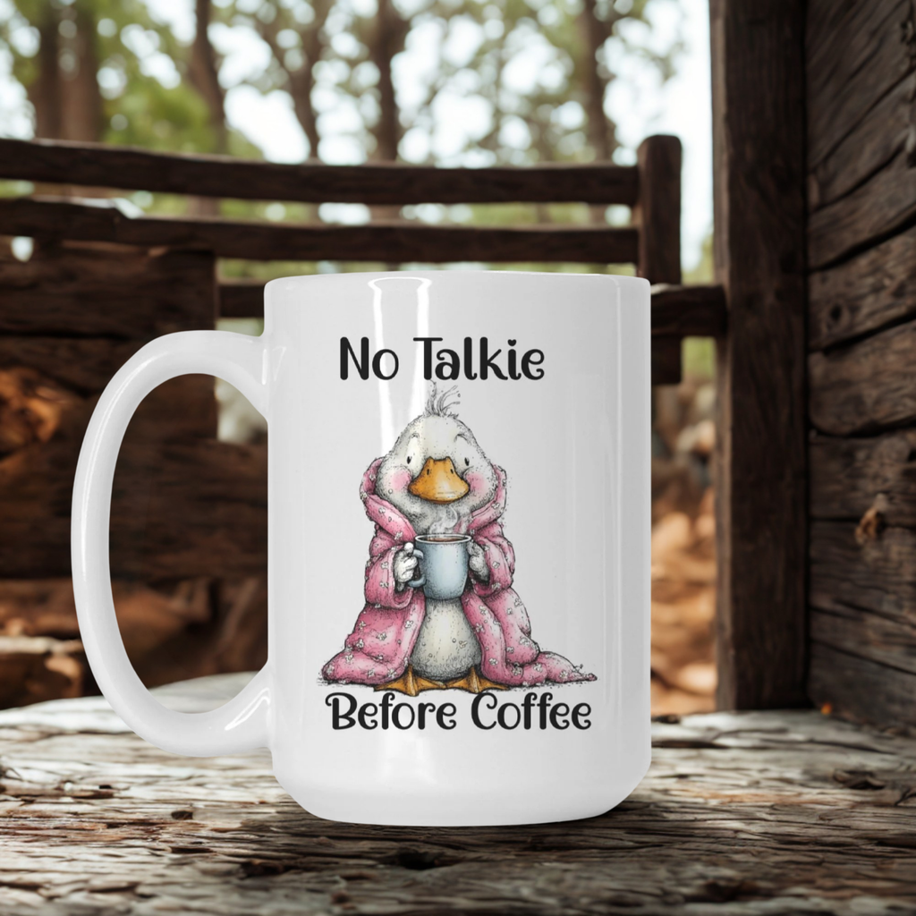 White mug with a cartoon duck in a pink robe and 'No Talkie Before Coffee' text, set against a wooden background.