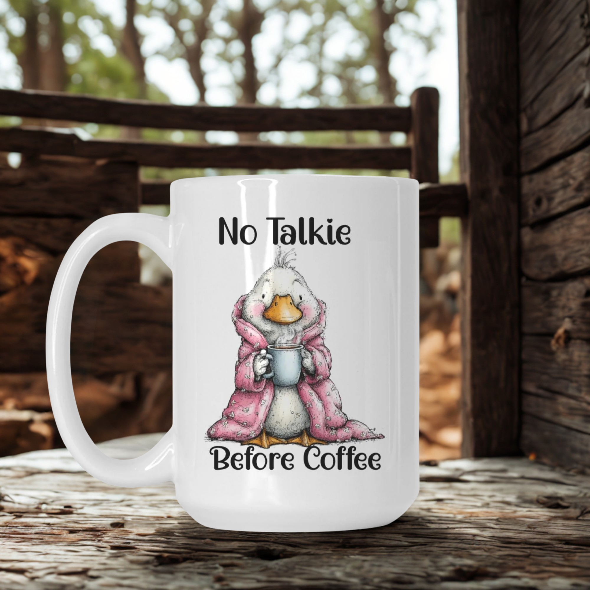 White mug with a cartoon duck in a pink robe and 'No Talkie Before Coffee' text, set against a wooden background.