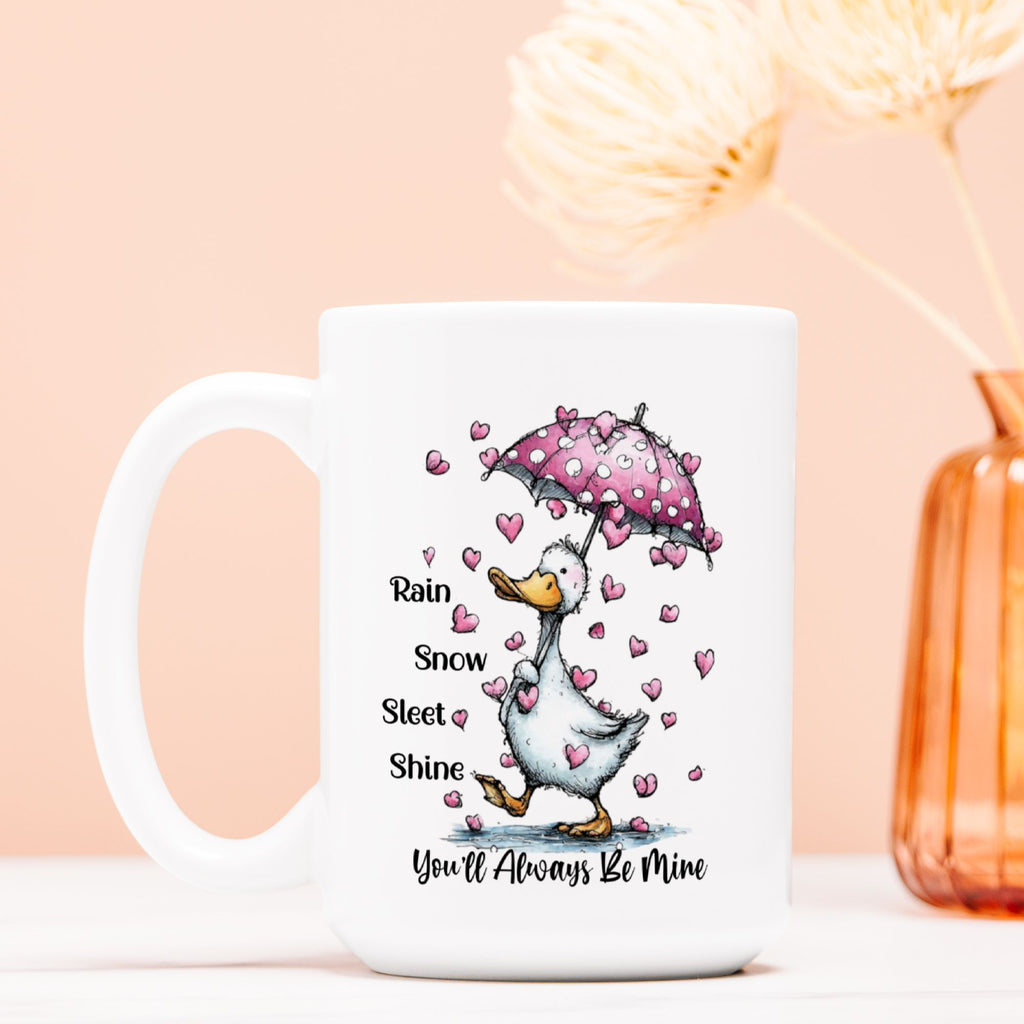 Mug with a cartoon duck holding an umbrella and hearts, text 'Rain Snow Sleet & Shine You'll Always Be Mine' on a peach background.