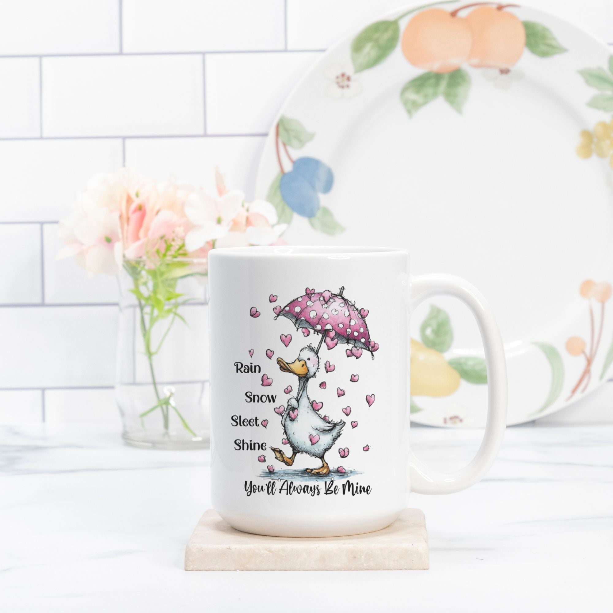 Mug with a cartoon goose holding an umbrella and hearts, placed on a wooden coaster with a decorative plate in the background.