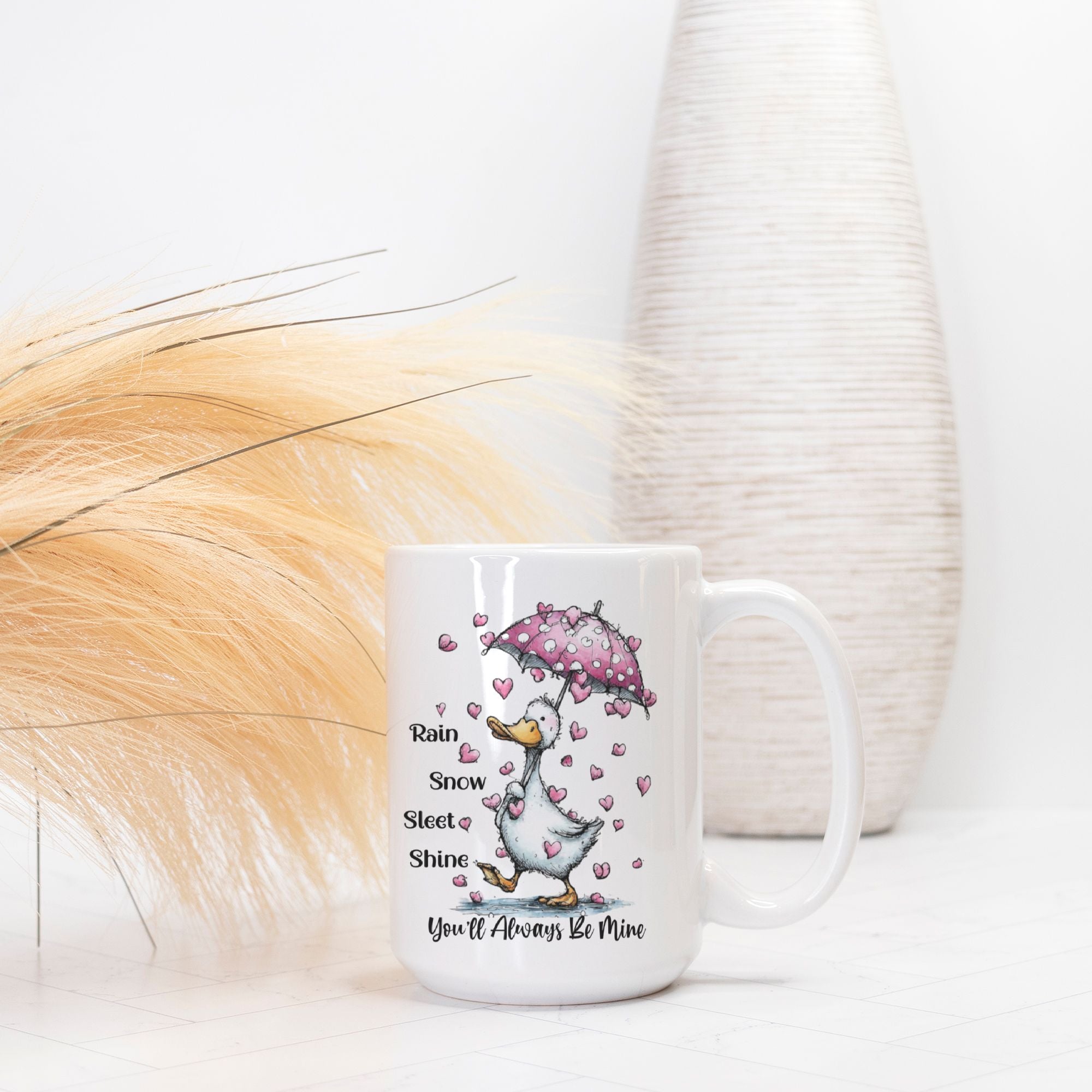 Mug with a cartoon goose holding an umbrella and hearts, text 'Rain or Snow, Sleet or Shine, You'll Always Be Mine' on a white background.