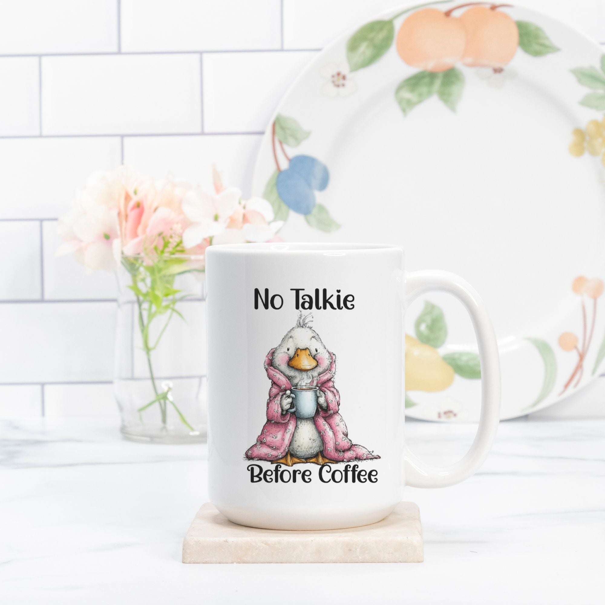Mug with a cartoon duck wearing a raincoat and holding a coffee cup, with text 'No Talkie Before Coffee' on a white surface.