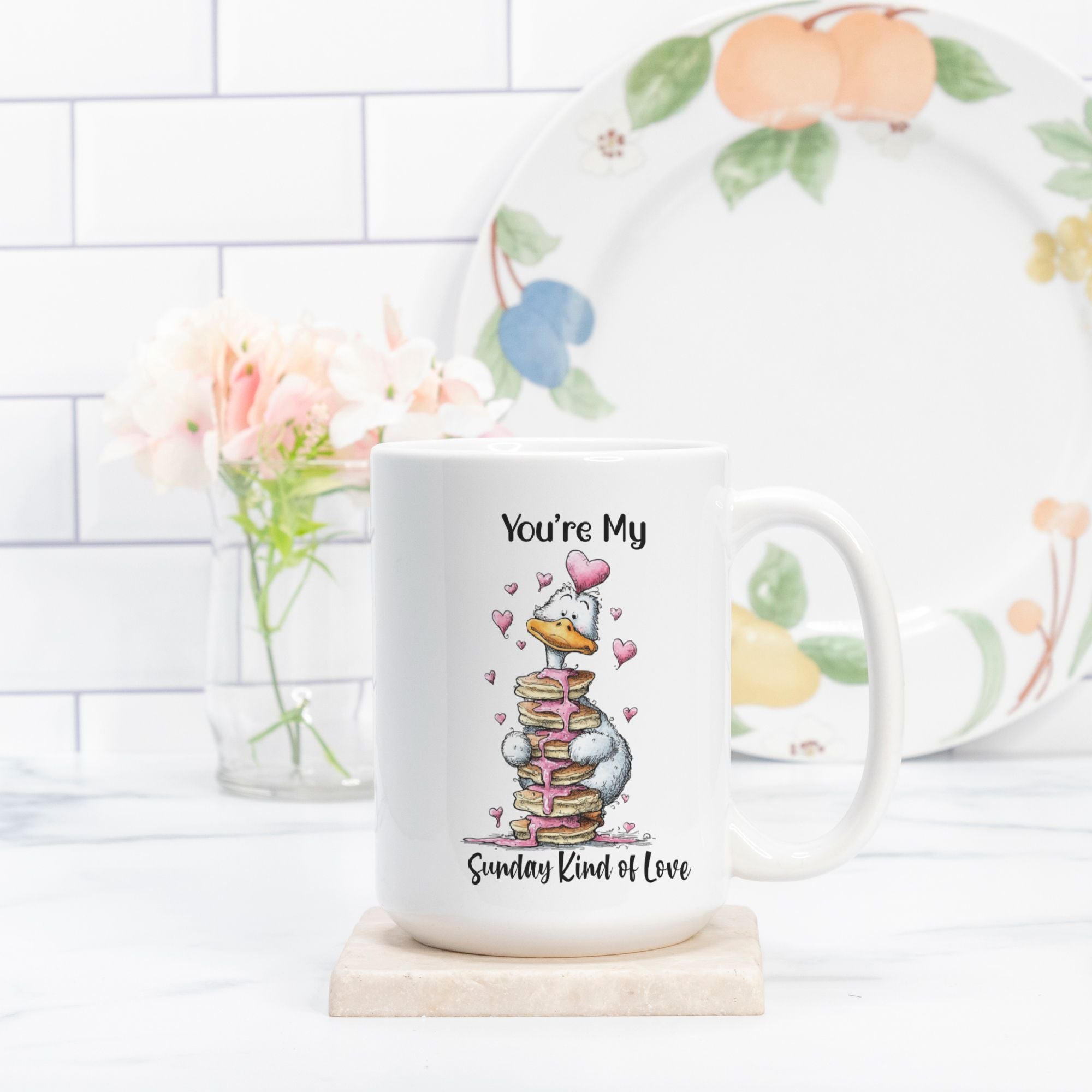 Mug with a cartoon goose design and text on a white surface with a decorative plate in the background.