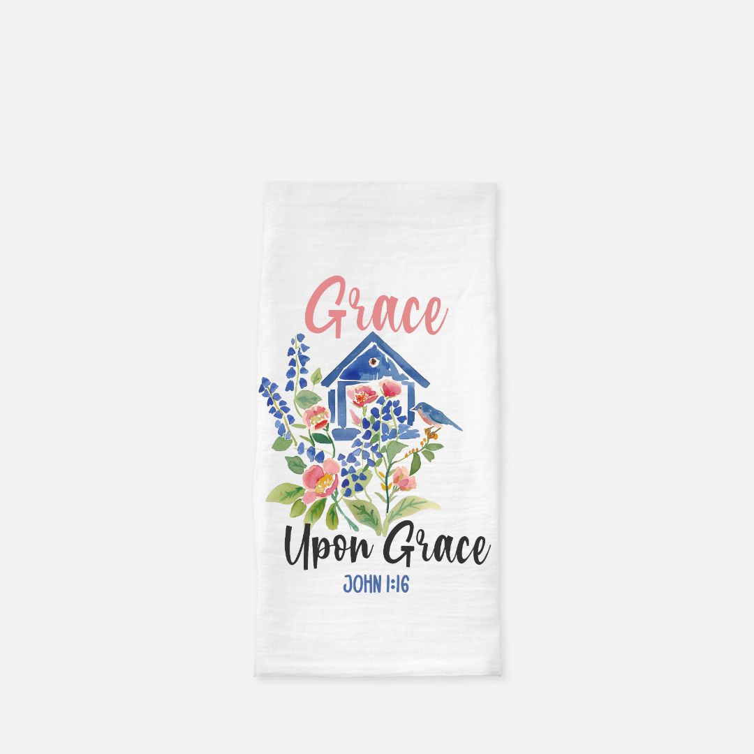 Decorative tea towel with a blue birdhouse, bird, and floral design, featuring the text 'Grace Upon Grace John 1:16' on a white background.
