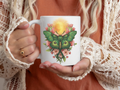Person holding an 11oz. mug with a green lunar moth design against a brown background