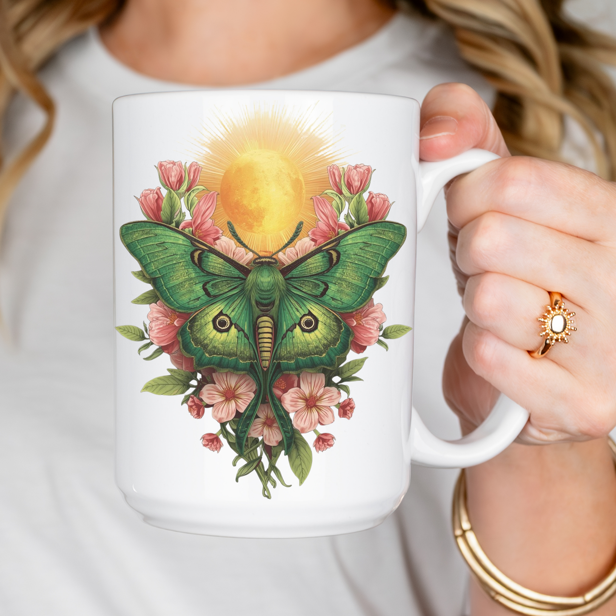Person holding a mug with a green lunar moth and floral design.