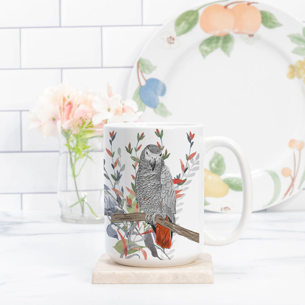 Mug with a parrot design on a marble surface with a floral plate in the background.