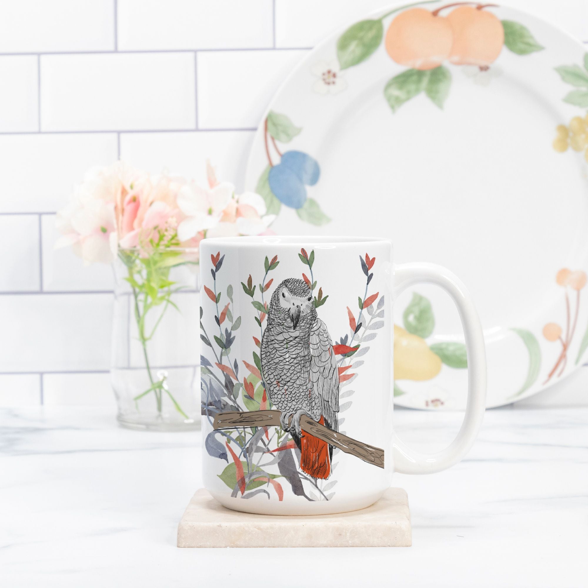 Mug with a parrot design on a marble surface with a floral plate in the background.