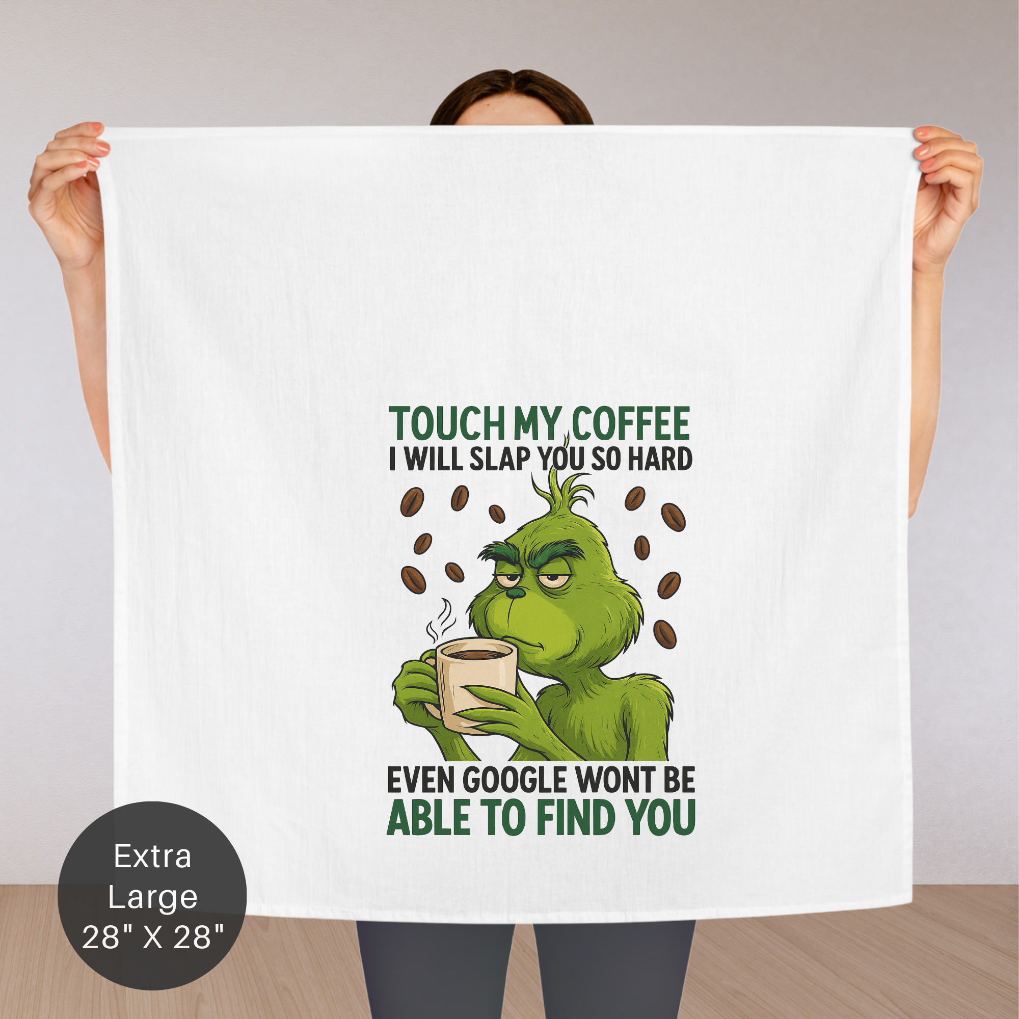 Person holding a large towel with a Grinch design and humorous text.