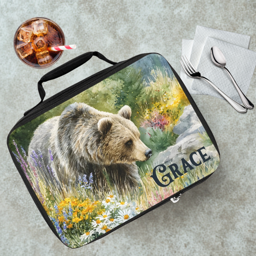 Lunch bag with bear design and 'Grace' custom text on a cafeteria table with a drink and utensils.