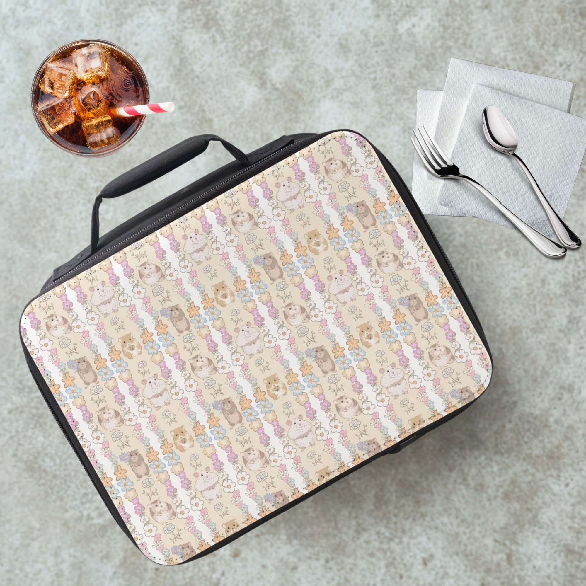 Hamster patterned lunch bag on a cafeteria table with a drink and utensils.