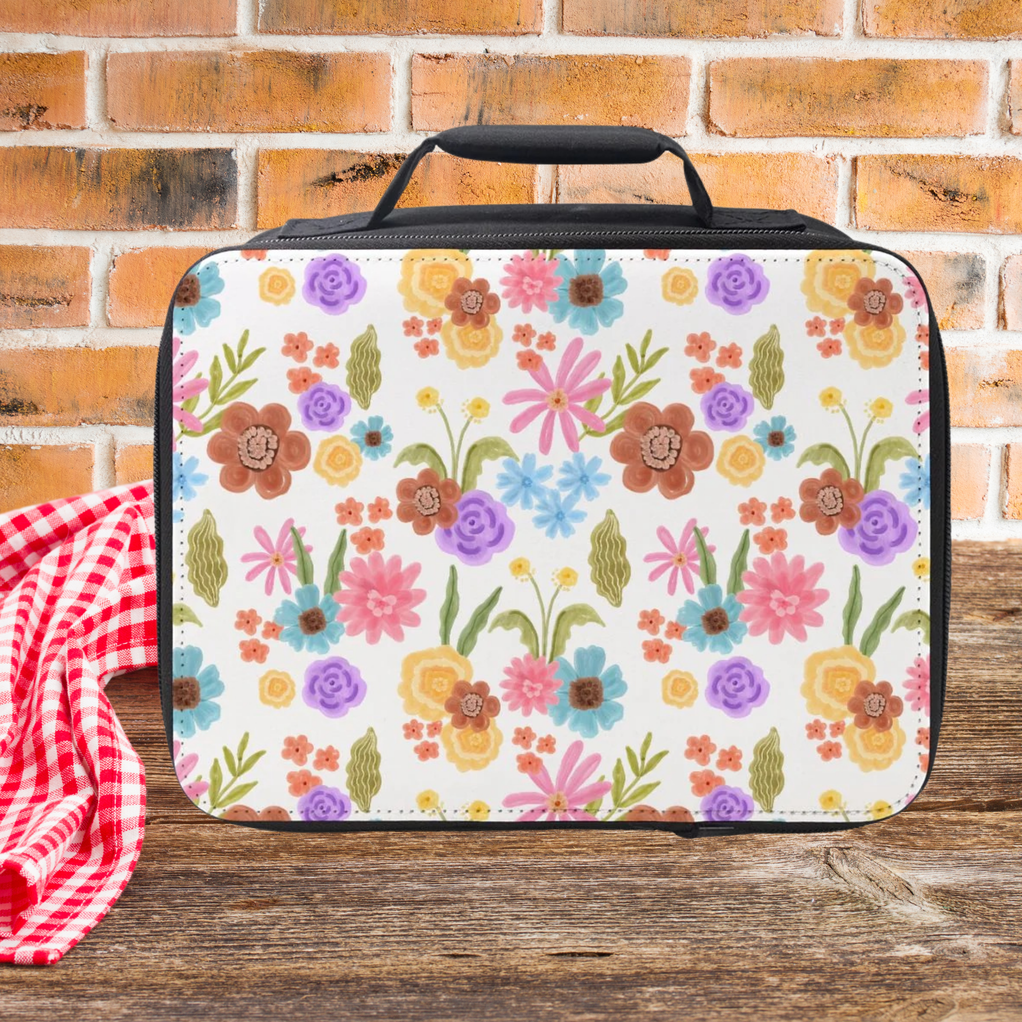 Floral-patterned lunch bag on a wooden picnic table with a brick wall background